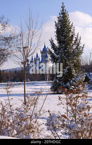 Retro castillo azul detrás de los árboles bajo la nieve en invierno Foto de stock