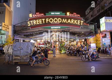 Entrada al mercado nocturno Ben Thanh, con gente en las motos, la forma de transporte más popular en Vietnam Foto de stock