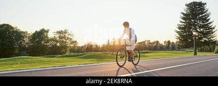 Vista trasera del hombre atlético en Sportswear de pie con bicicleta en la carretera. Montar en bicicleta de montaña en un soleado día de verano. Estilo de vida activo saludable y concepto deportivo Foto de stock