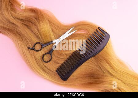 Cabello Artificial Rojo sobre fondo rosa, comba y tijeras. El concepto de  peinado, corte de pelo Fotografía de stock - Alamy