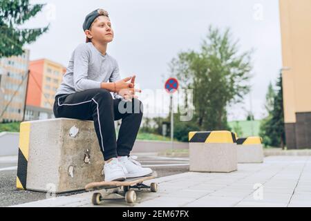 Adolescente patinador niño retrato en una gorra de béisbol con skateboard viejo en la calle de la ciudad. Generación de jóvenes Gasto en tiempo libre y gente activa