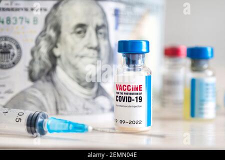 Vacuna contra la infección por coronavirus Covid-19 y una jeringa sobre la mesa contra el fondo del dinero. El concepto de producción de vacunas de alto costo. Foto de stock