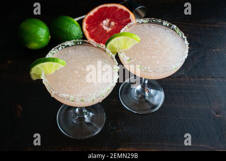 Hemingway Daiquiris (Papa Dobles) pescado con lima: Dos cócteles de ron, lima y pomelo servidos en vasos coupé con borde de azúcar Foto de stock