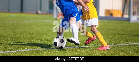 Los jugadores de fútbol compiten por un balón. Niños jugando Deportes en Grass Pitch. Dos niños en duelo de fútbol en Sideline. Imagen de primer plano de Youth Football Comp
