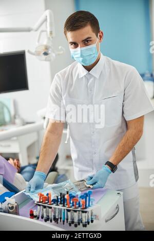 Hombre en blanco peelings obtener herramientas dentales de la bolsa de plástico Foto de stock