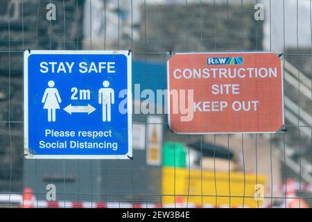 Reino Unido 2 metros de distancia social Covid signo & Keep Out signo en la valla de malla de un sitio de proyecto de ingeniería civil. Para la industria de la construcción en el Reino Unido durante Covid Foto de stock