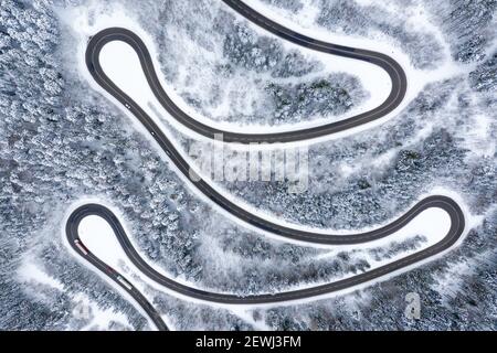 Invierno nieve carretera serpenteante Serpentine switchbacks bosque bosques temporada vista aérea foto drone.