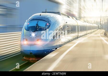 El tren de pasajeros eléctrico conduce a alta velocidad sale de la plataforma Foto de stock