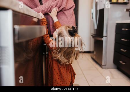 La niña llega para su mamá en la cocina familiar