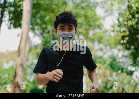 Un joven asiático deportivo con máscara facial mientras se jogaba en el parque. Enfoque selectivo.