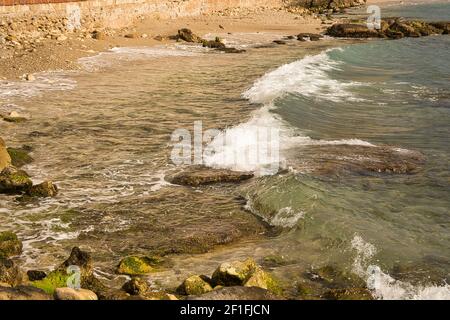 Las olas del mar lash line impactan la roca en la playa, situada en Alicante, España, Foto de stock