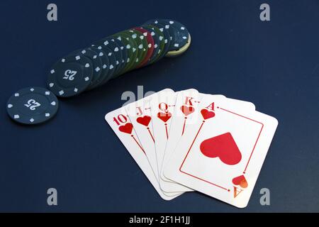 Una vista superior de las cartas y fichas reales de corazón uniformemente organizado en una mesa de póquer Foto de stock