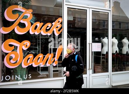 Señal que dice 'Back Soon' en la ventana de una tienda cerrada en el centro de la ciudad de Edimburgo, como las medidas de bloqueo para la Escocia continental continúan. Fecha del cuadro: Jueves 11 de marzo de 2021. Foto de stock