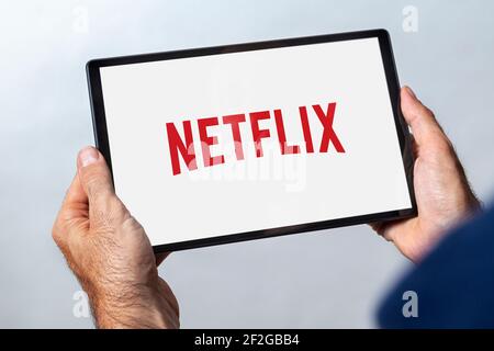 ROSARIO, ARGENTINA - 11 DE MARZO de 2021: Hombre sosteniendo una tableta con el logo del servicio de transmisión de vídeo netflix en la pantalla. Foto de stock