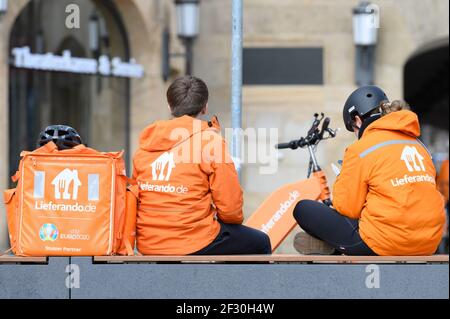 Dresde, Alemania. 13th de marzo de 2021. Dos mensajeros de bicicleta del servicio de entrega Lieferando se sientan junto a una mochila en la Plaza de correos. Crédito: Sebastian Kahnert/dpa-Zentralbild/dpa/Alamy Live News Foto de stock
