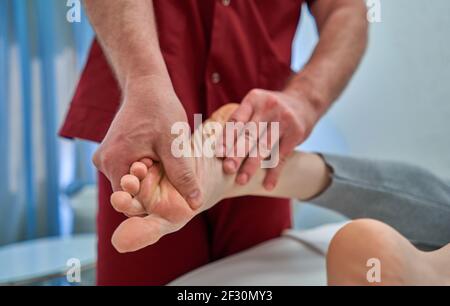 Trabajador de la salud dando masaje pies ortopédicos para mujer Foto de stock