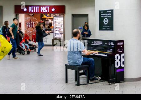 Un miembro del público tocando un piano vertical en el patio de billetes de la estación de metro King's Cross, Londres, Reino Unido Foto de stock