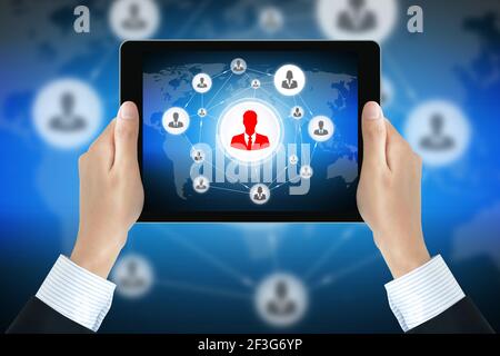 Businessman tiene las manos sosteniendo el tablet pc con los iconos de los empresarios vinculados como red en la pantalla - red social y de negocios en línea conceptos
