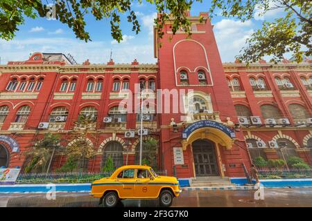 Taxi amarillo frente al edificio de la Corporación Municipal del Gobierno construido en estilo de arquitectura colonial en Kolkata, India