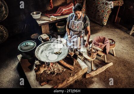 Mujer hace tortillas de maíz a mano y cocineros en un comal de barro grande  Fotografía de stock - Alamy