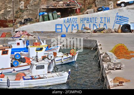 El pequeño puerto pesquero de la isla Thymena, junto a las islas de Samos, Ikaria y Fourni, en Grecia, Europa. El signo dice "Bienvenido a Thymena", en griego Foto de stock