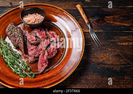 Onglet asado a la parilla carne tierna carne filete de ternera en un plato. Fondo de madera oscura. Vista superior. Espacio de copia Foto de stock