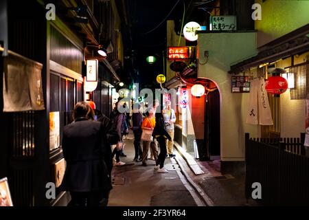 Kioto, Japón - 16 de abril de 2019: Gente caminando por la calle del barrio del callejón de Pontocho en la noche oscura con faroles iluminados y restaurantes de izakaya Foto de stock