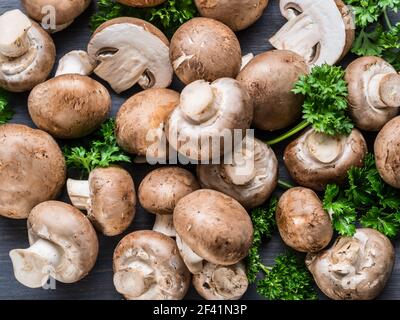 Champiñones comestibles de color marrón o champiñones cremini sobre mesa de madera con hierbas. Vista superior. Foto de stock