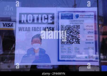 Durante un brote de COVID - 19, un signo bilingüe en la entrada de una tienda de advertencia a las personas a usar máscaras / cubiertas durante la pandemia de coronavirus. Phnom Penh, Camboya. © Kraig Lieb Foto de stock