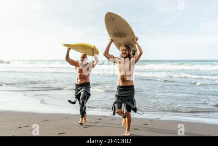 Felices amigos con diferentes edades surfing juntos - Sporty people Divertirse durante el día de surf de vacaciones - estilo de vida deportivo extremo concepto Foto de stock