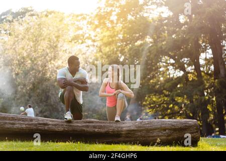 Una pareja de raza negra se estira después de hacer ejercicio en el tronco del árbol