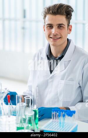 Hombre científico sonriente sentado en el escritorio mientras trabajaba laboratorio