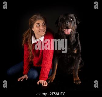 purebred rottweiler y mujer delante de fondo negro