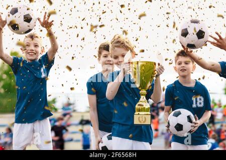 Celebración del equipo de fútbol. Niños alegres celebrando el éxito en el Juego del Torneo de Fútbol. Junior Sports Team Rising Golden Trophy en Confetti Celebr