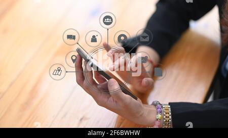 Vista de cerca de una empresaria que sostiene un smartphone con iconos de aplicaciones alrededor.