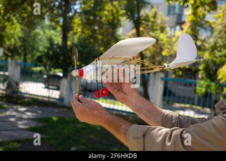 Modelo de avión con hélice de plástico de residuos domésticos sobre un fondo del cielo en las manos de abuelo Foto de stock