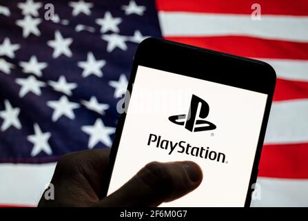 En esta ilustración de la foto, el logotipo de la Marca japonesa de videojuegos creada y propiedad de Sony Computer Entertainment, PlayStation, se ve en un dispositivo móvil Android con la bandera de Estados Unidos de América (EE.UU.), comúnmente conocida como Estados Unidos (EE.UU. O EE.UU.), en el fondo. Foto de stock