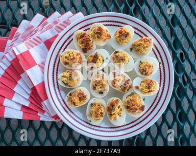 Vista superior de un plato redondo de huevos devorados con servilletas en una mesa de picnic al aire libre