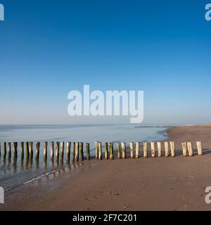 fila de polos en la playa de zeeland en los países bajos bajo el cielo azul en primavera Foto de stock