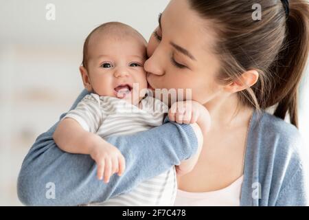 Amor de la Madre. Retrato de primer plano de la mamá joven besando a su hija recién nacida del Cute Foto de stock