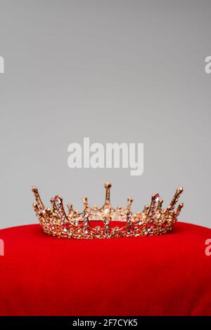 corona real dorada sobre cojín de terciopelo rojo aislado en gris Foto de stock