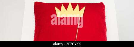 vista superior de la corona de papel en el palo y almohada de terciopelo rojo en gris, banner Foto de stock