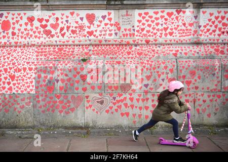 Una joven monta un scooter por el National Covid Memorial Wall en el terraplén de Londres. Más de mil personas, incluyendo a los afligidos, personal del NHS, voluntarios y miembros del público, han estado pintando 150.000 corazones en la pared, que ahora se extiende alrededor de medio kilómetro, para representar a los seres queridos perdidos por el virus en el Reino Unido. Fecha de la foto: Jueves 8 de abril de 2021.