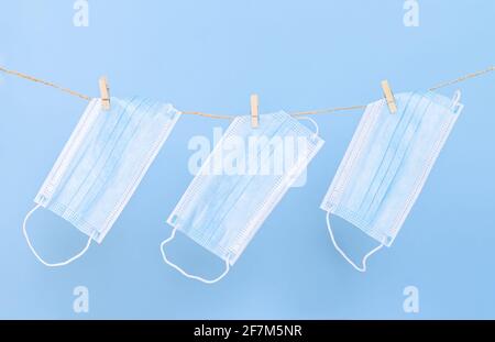Mascarillas protectoras lavables, utilizadas para la protección contra virus, colgadas en la línea de lavado con clothespins Foto de stock