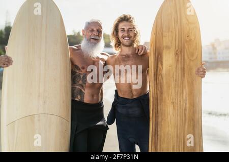 Felices amigos en forma con diferentes edades navegando juntos - Sporty Gente que se divierte durante el día de surf de vacaciones - deporte extremo concepto de estilo de vida Foto de stock
