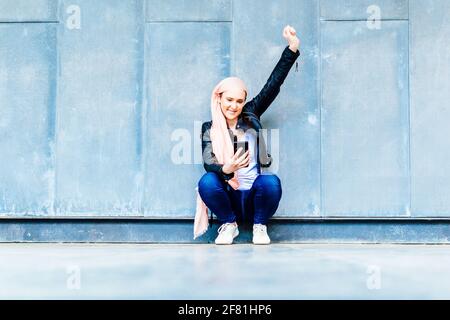 Mujer feliz sonriente con cáncer y pañuelo rosa levantando uno brazo en símbolo del concepto de victoria para vencer y vencer cáncer Foto de stock