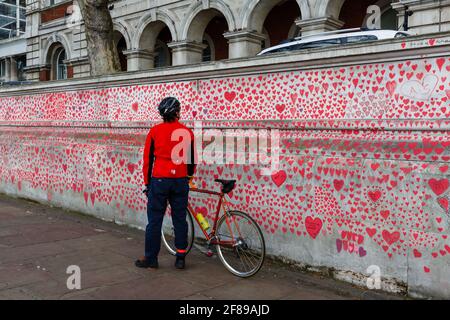 Los transeúntes observan los corazones rojos pintados en el Nacional Covid Memorial Wall como homenaje a las víctimas británicas De Corornavirus Foto de stock