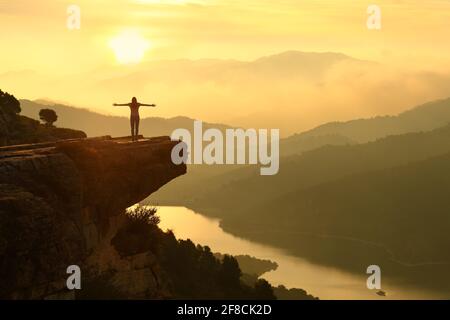 Vista posterior retrato de una silueta de mujer que celebra el éxito en un hermoso paisaje al atardecer