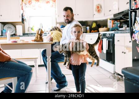 Pequeña niña sosteniendo su lindo gato mascota en ella brazos en la cocina