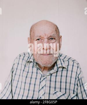 un retrato grande de un anciano sobre un fondo claro con arrugas profundas, manchas de edad. Foto de stock